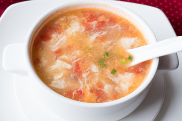 Traditional Chinese soup with tomatoes and egg in a white plate. Shallow depth of field.