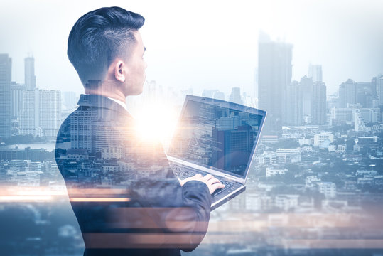 The double exposure image of the business man using a laptop computer during sunrise overlay with cityscape image. The concept of modern life, business, city life and internet of things.