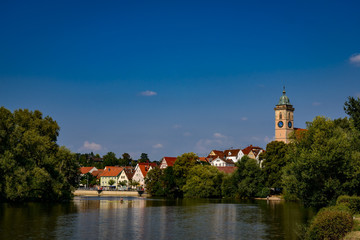 Fototapeta na wymiar Ruderboot auf dem Neckar vor der Kulisse der historischen Altstadt von Nürtingen mit dem Turm der St. Laurentius-Kirche, Blick von Westen