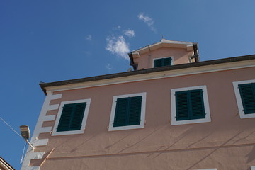 Old traditional pink painted building with green wooden sunshades