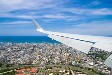 Wing of airplane in the air flying over city