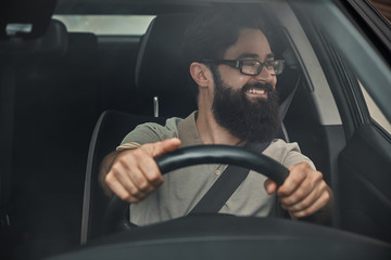A modern bearded man driving a car