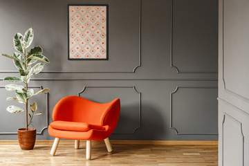 Real photo of open space dark grey living room interior with poster hanging on wall with...