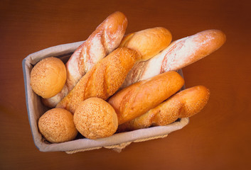 Fresh wheat bread in basket on wooden surface. Top view.