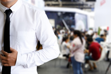 Men's white shirt standing in front blurred people siting