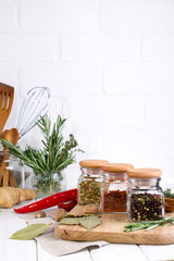 Cooking table with spices in glass jars  and herbs.  On white background