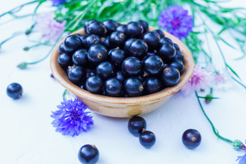 Fresh berries of black currant in a plate on a table. For a diet and saturation with vitamins