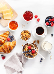 healthy breakfast with granola, berry, nuts, croissant, jam, chocolate spread and coffee. Top view