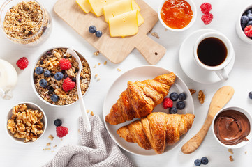 healthy breakfast with granola, berry, nuts, croissant, jam, chocolate spread and coffee. Top view
