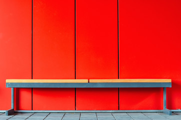 Wooden bench on creative red background. Copy space.