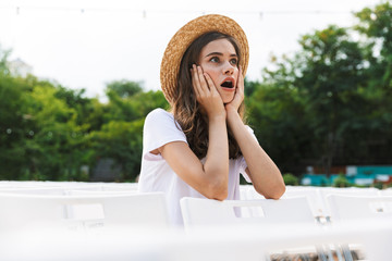 Amazed young girl sitting at the city park outdoors