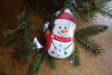 Classic snowman made of gingerbread and spruce branch on wooden table