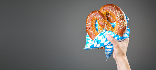 Oktoberfest concept - hands holding beer and pretzel - obrazy, fototapety, plakaty