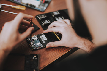 Close up Young Man Repairing Mobile Phone at Table