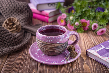 Fruit tea, books, knitted sweater and flowers asters on a wooden background