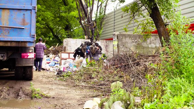 Robotic arm of garbage truck taking gabbage and putting it in the truck's body
