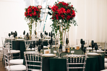 Tall bouquets of roses stand on dark green tables in restaurant hall