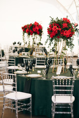 Tall bouquets of roses stand on dark green tables in restaurant hall