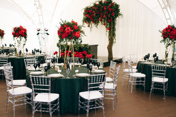 Tall bouquets of roses stand on dark green tables in restaurant hall