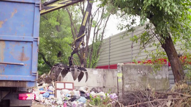Robotic arm of garbage truck taking gabbage then putting it at the another place