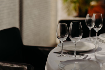 Serving, celebration, anniversary or wedding concept. Glassware and cutlery on festive table in banquet hall of luxury restaurant. Cozy interior