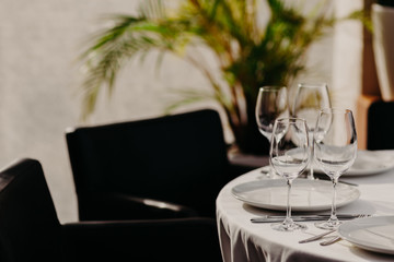 Table setting for dining. Beautiful served table for dinner or supper for special occasion. White tableclothes. Empty dishes. Cozy atmosphere