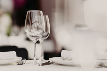 Served restaurant table with cutlery and wine glasses against blurred background. Banquet table for...