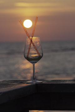 In Focus, Semi Empty Cocktail Glass, On A Shiny And Blury Tropical Sea Background