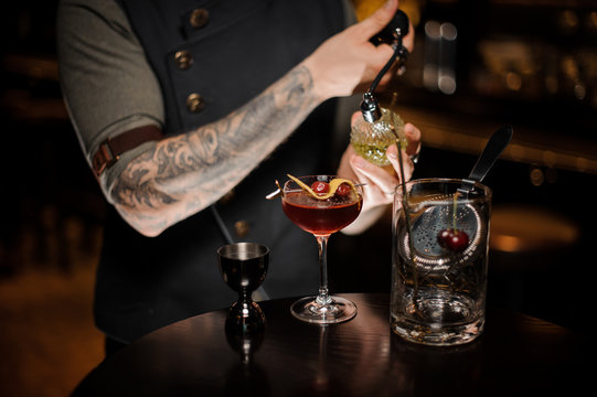 Barman making a fresh and sweet summer cocktail with cherries