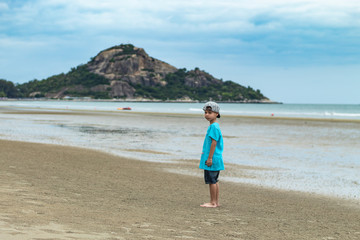 Asian boy walking on the beach by the sea