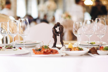 Little figures of hugging man and woman stand in the middle of dinner table