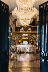 Luxury golden chandeliers hang over rich dinner hall in the restaurant