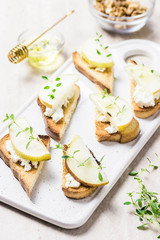 Goat cheese, pear, honey crostini on marble background. Selective focus, space for text.