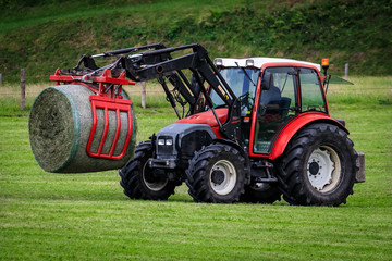 Obraz premium Traktor auf dem Feld bei der Heuernte