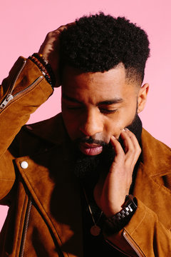 Stylish, handsome and cool African American man with beard, isolated on pink studio background