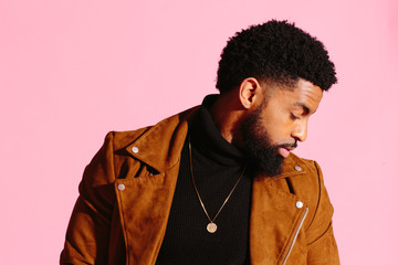 Stylish, handsome and cool African American man with beard, isolated on pink studio background