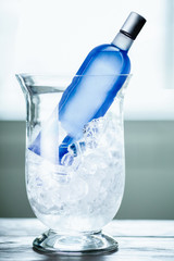 Blue bottle with vodka in cooler with ice.