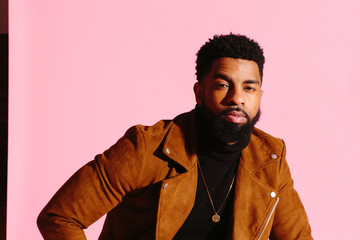 Stylish, handsome and cool African American man with beard, isolated on pink studio background