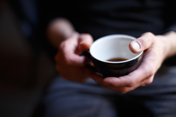 Man holds cup of coffee with two hands. Feels comfort, heat and home furnishings.