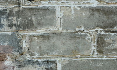 Grey brick wall with ancient scretches and damages.
