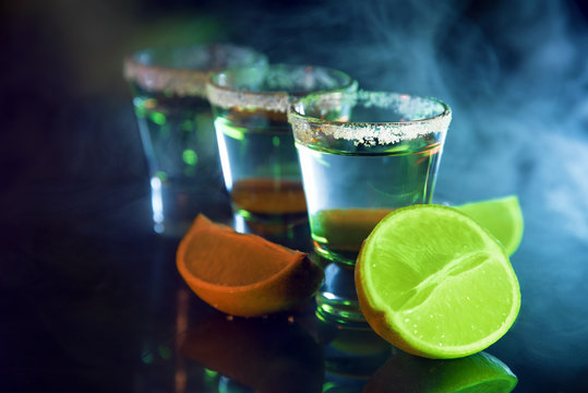 Tequila and lime slices in a bar on a background of smoke