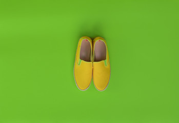 summer yellow shoes on isolated green background, abstract concept