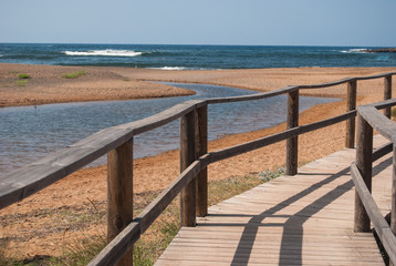 Fototapeta na wymiar Wooden path on the beach of Binimella cove in Menorca