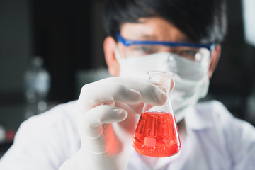 Student boy holding erlenmeyer flask chemistry equipment with red liquid benzene oil energy in...