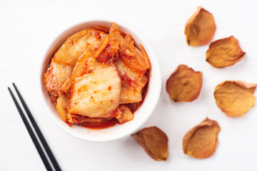 Kimchi cabbage in a bowl with chopsticks, top view, Korean food