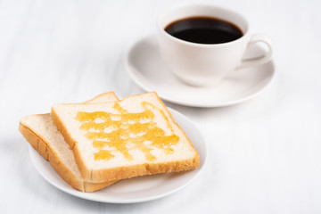 Sliced bread with honey topping and cup of black coffee on white table, delicious breakfast