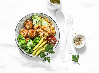 Healthy balanced buddha bowl lunch - spicy couscous with chickpeas, broccoli, green beans and turkey meatballs on light background, top view. Flat lay
