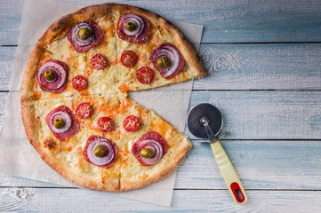 Pizza with salami and cheese on a wooden light background. Copy space for text