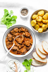 Irish beef stew and turmeric potatoes - delicious seasonal lunch on a light background, top view. Flat lay