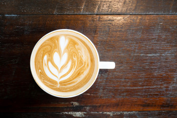 Cup of latte art coffee on wooden table in the coffee shop, top view